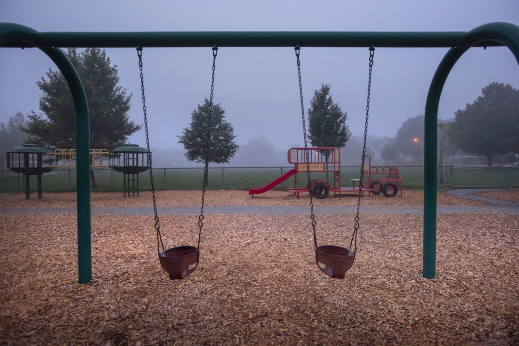 Horizontal color photograph of a childrens playground at dawn with fog. Belmont, MA